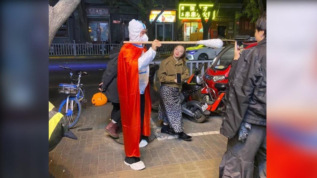 北京有人扮裝成核酸檢測人員,手拿幾乎有半個人高的超大型檢測棉花棒。(圖/翻攝自@iPaulCanada推特)
