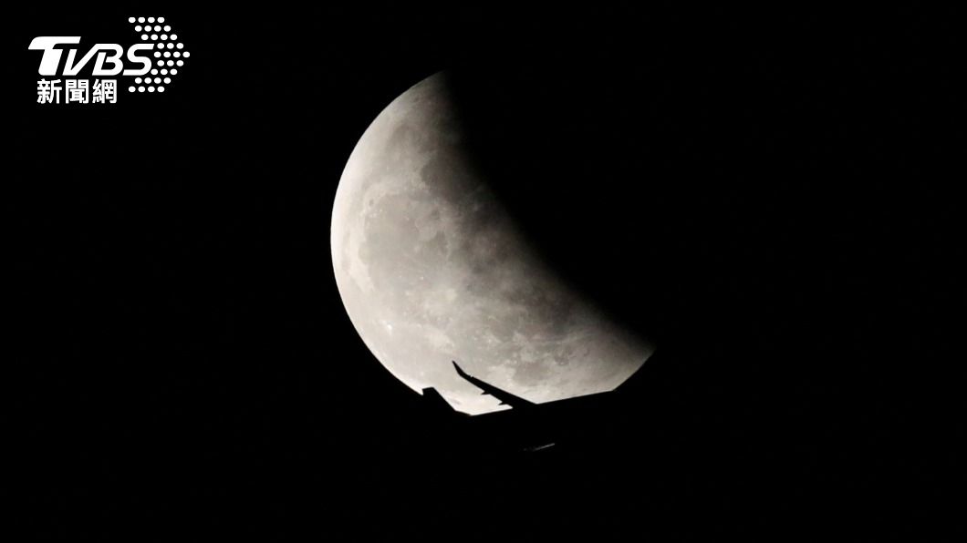 泰國一架飛機在月食期間飛過夜空,畫面宛如電影場景。(圖/達志影像路透社)