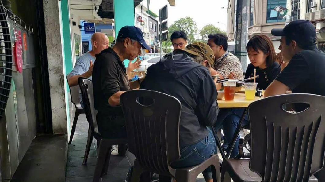 李安(戴帽者)在路邊享用美食。(圖/翻攝自黑光乍現微博)