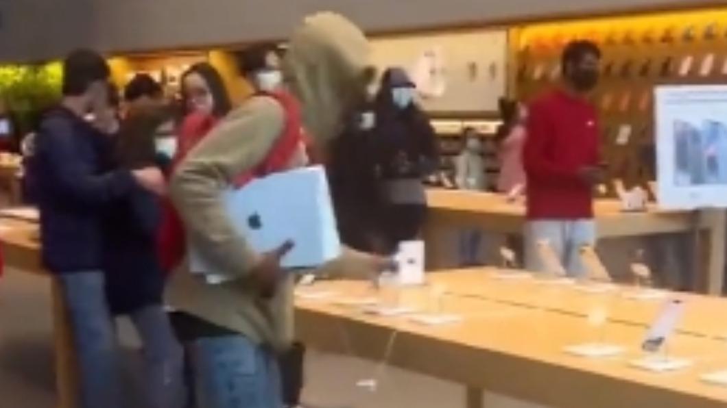 搶匪手上抱著筆電,另一手還在拆iPhone展示機。(圖/翻攝自PPV-TAHOE - News Journalist 推特 @ppv_tahoe)