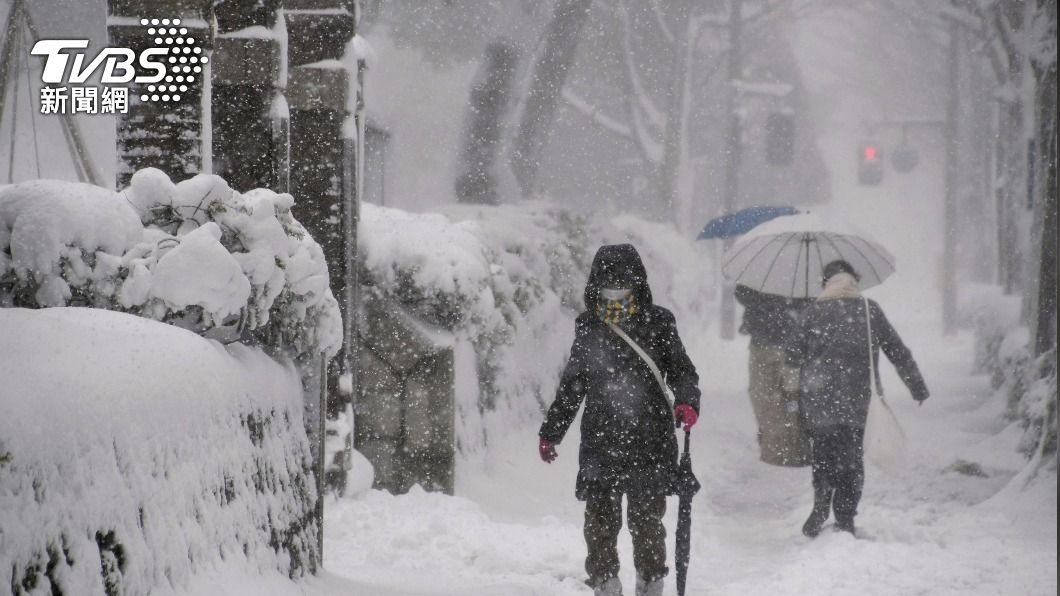 日本民眾在雪中緩緩徐行,路邊的積雪已經幾乎有半個人高。(圖/達志影像路透社)