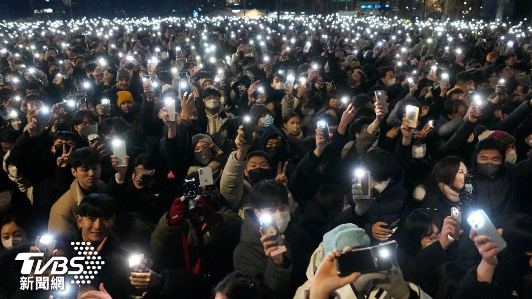 南韓民眾在普信閣外打開手機手電筒一起祈福。(圖/達志影像美聯社)