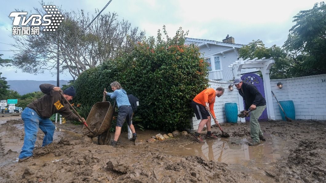 接連不斷的大雨讓道路變得泥濘不堪,居民正在住宅前鏟土。(圖/達志影像美聯社)
