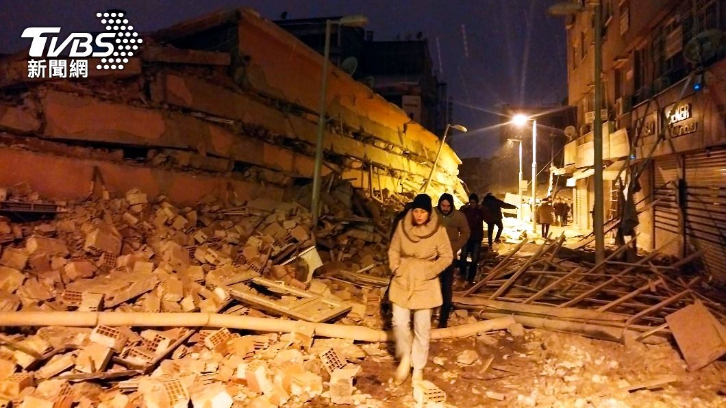民眾路過倒塌的建築物旁。(圖/達志影像美聯社)