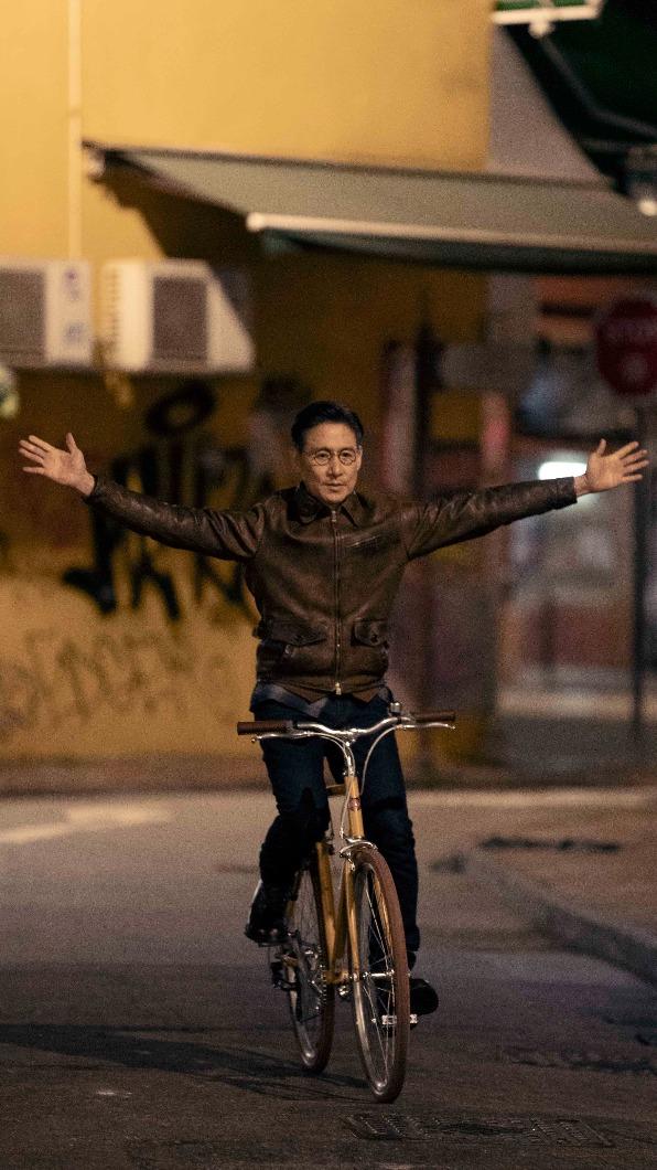 張學友應導演要求練習放手騎單車，卻因路面不平整而摔車。（圖／環球音樂提供）