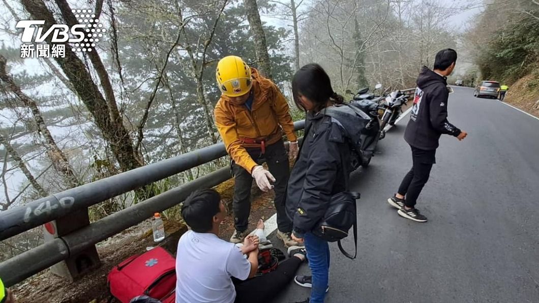女乘客被救上來有驚無險(黑衣站立者)男騎士腳踝受傷,吳峻德幫忙包紮,等待救護送醫。