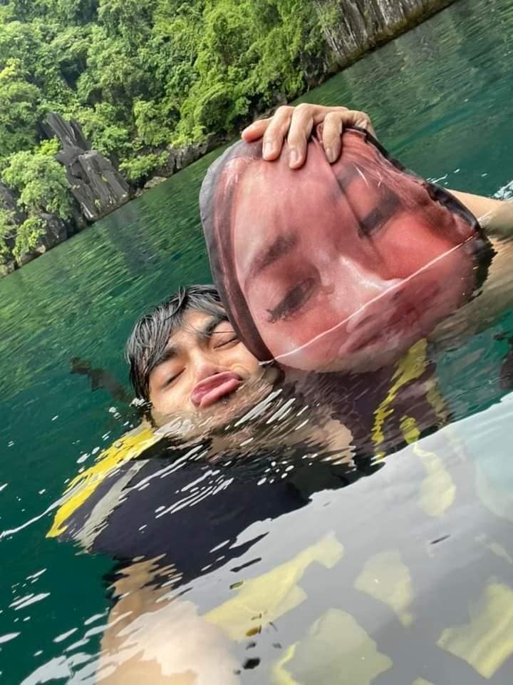 人夫連潛水也帶著老婆替身一起,抱枕浸濕也要同框拍照。(圖/翻攝自World of Buzz)