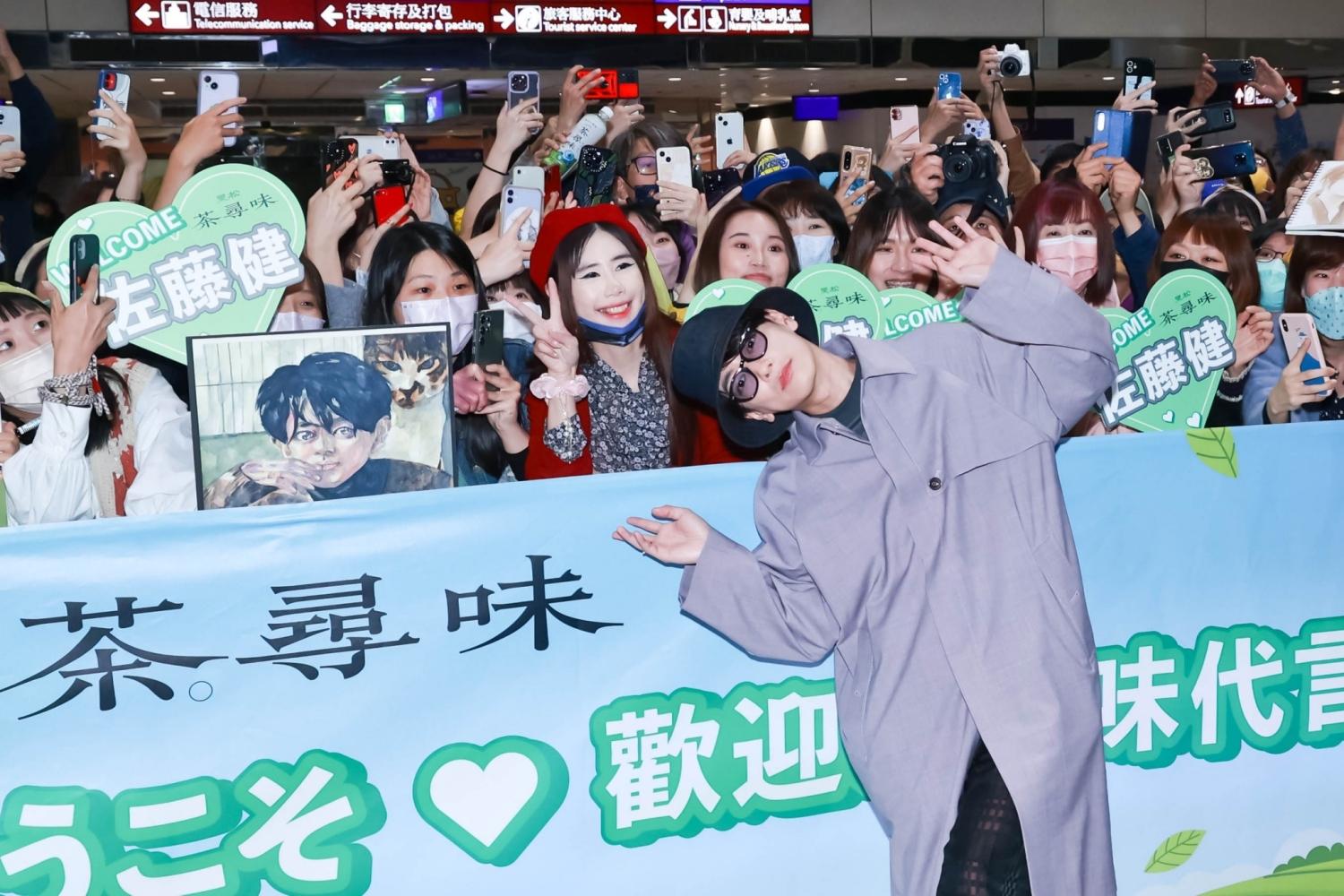 佐藤健一到桃園機場入境大廳就先跟粉絲合照,比出逗趣姿勢。(圖/趙世平攝)