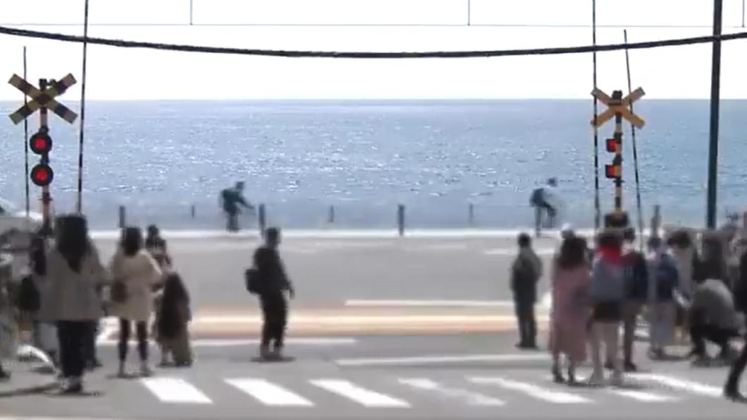 在江之島電鐵平交道拍照的遊客,不顧人身安全,大剌剌站在馬路中間拍照。(圖/翻攝自@58euzyk84g推特)