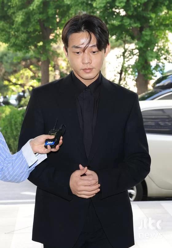 劉亞仁16日身穿全黑正裝接受調查,面對韓媒提問一概保持緘默。(圖/翻攝自JTBC)