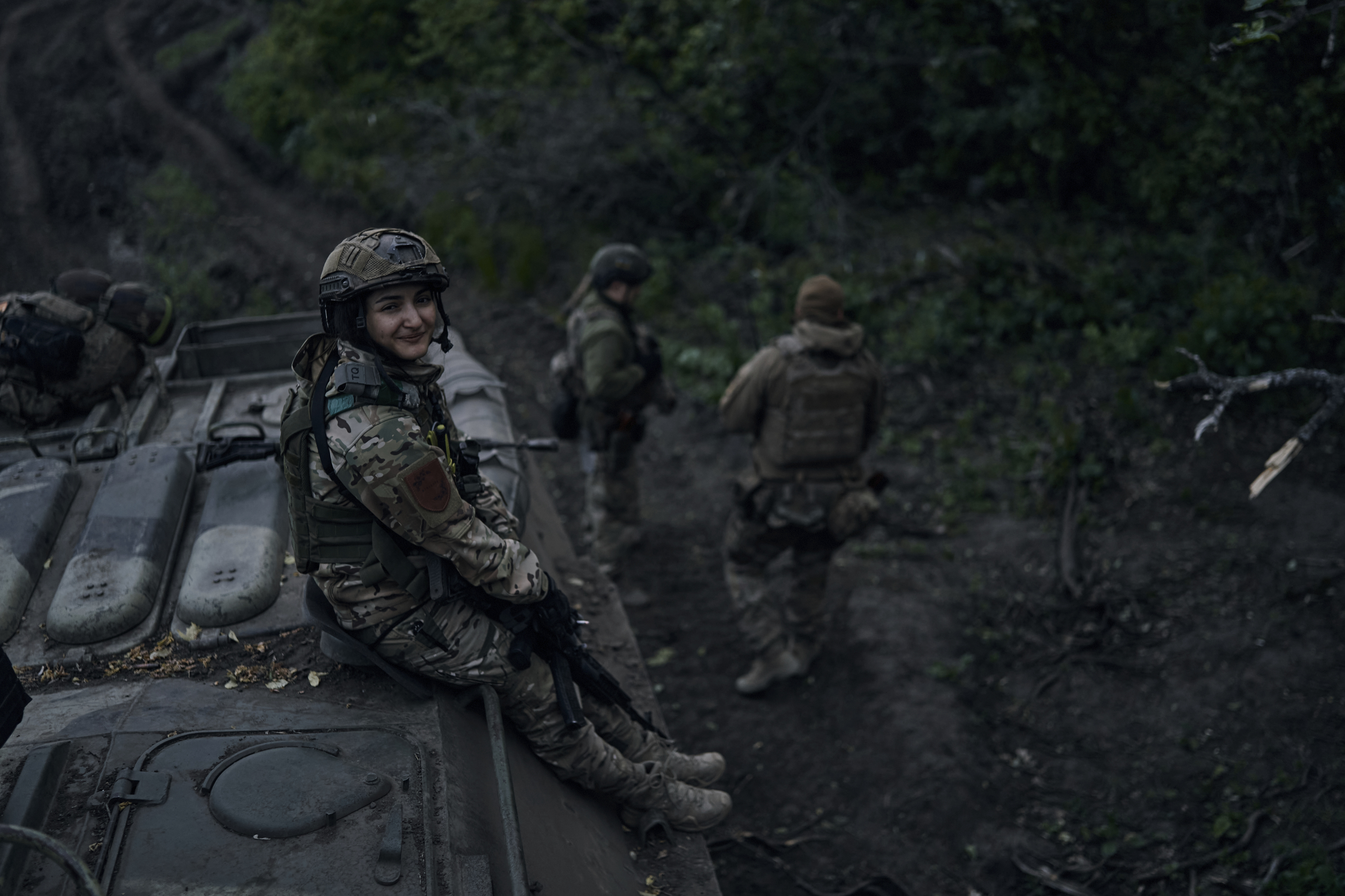 坐在裝甲運兵車上的烏克蘭女兵,在前線對著鏡頭微笑。(畫面來源:AP)