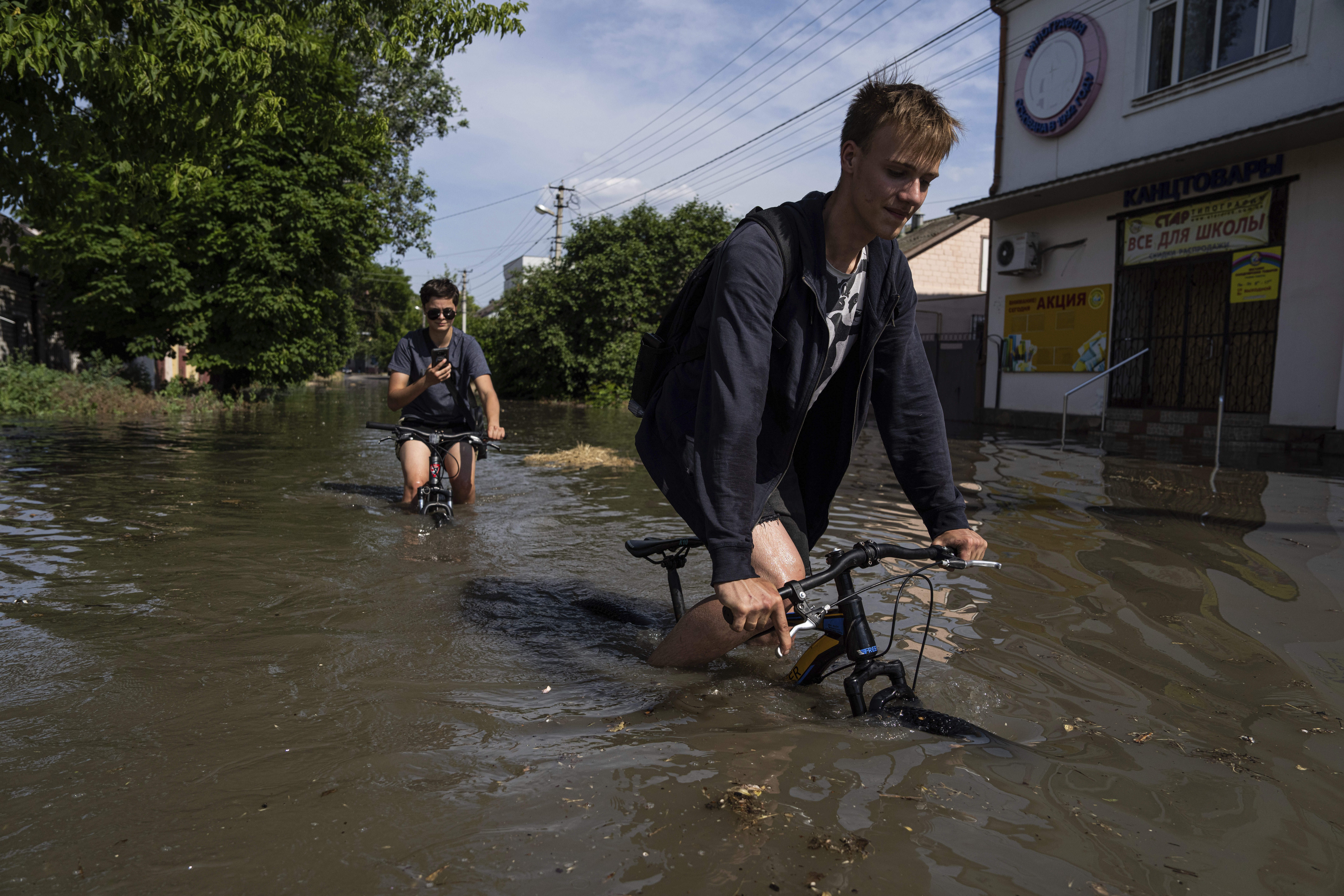 災區民眾騎著自行車通過淹水街道。(畫面來源:AP)