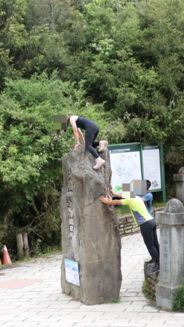 女子在男性友人的協助下攀爬石碑。(圖/翻攝自登山通報站臉書)