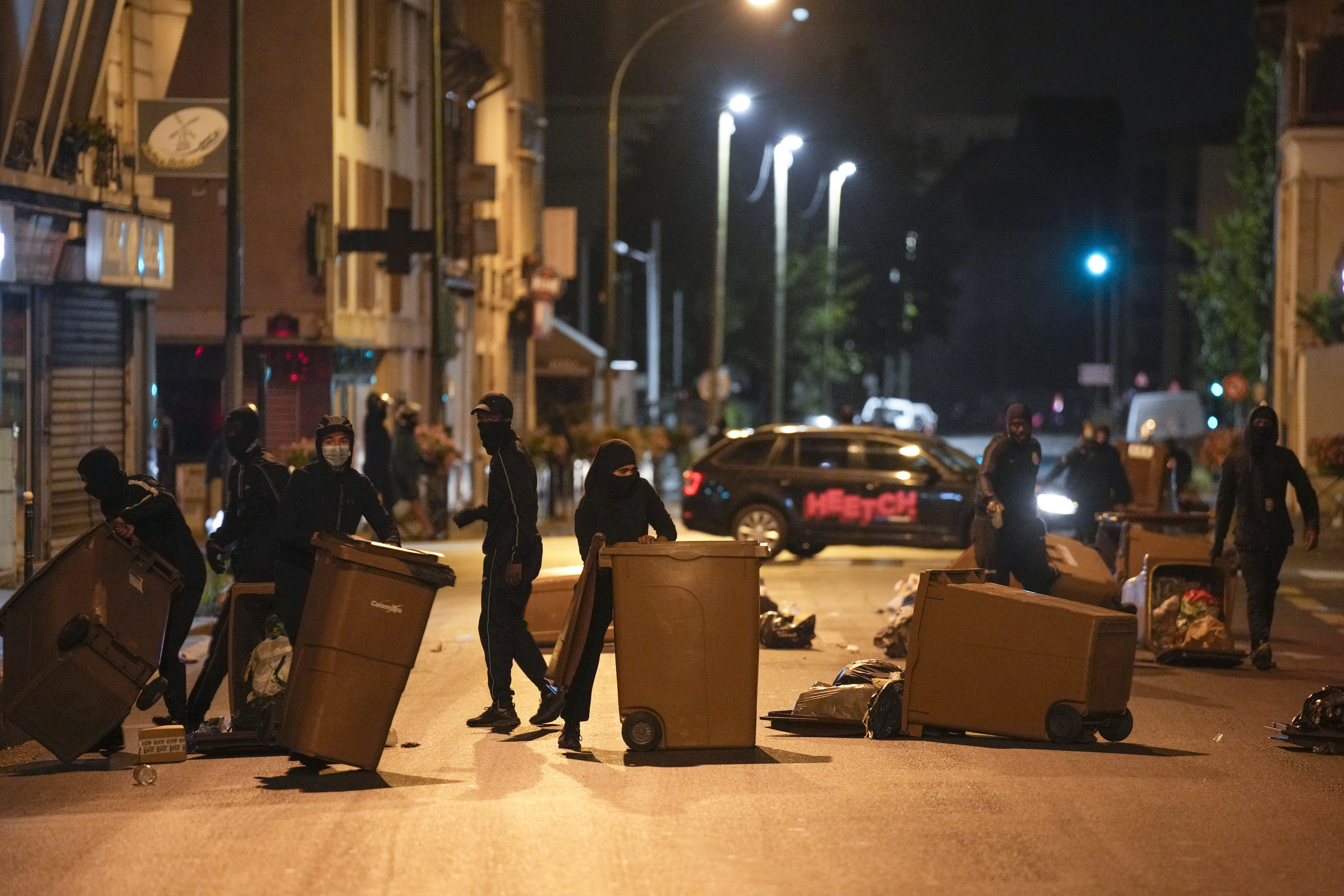 抗議民眾在深夜走上街頭,並且推倒垃圾桶做為路障,阻擋鎮暴警察的平亂行動。(畫面來源:AP)
