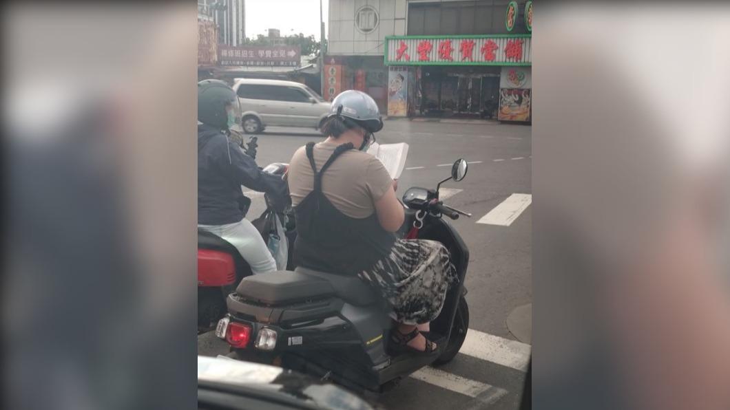 該名女騎士很會利用時間,在等紅綠燈時拿出書來看,被網友稱「亂世中的一股清流」。(圖/翻攝自路上觀察學院)