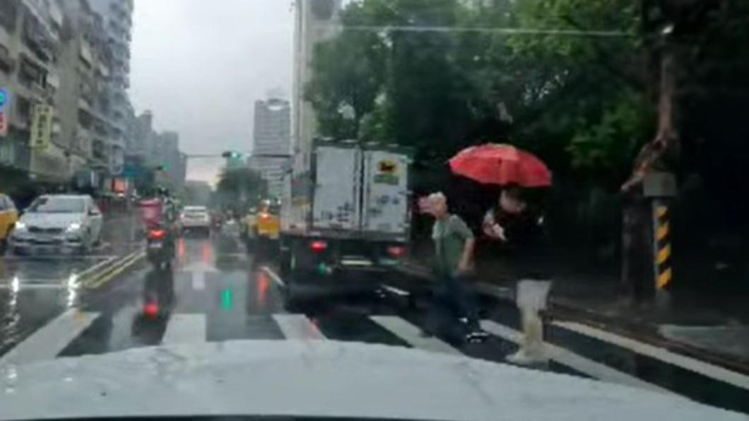 黑衣男熱心撐傘替阿嬤擋雨,並攙扶對方過馬路。(圖/翻攝自爆怨2公社臉書)