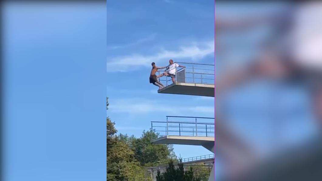 儘管男子試圖用手緊抓欄杆，但仍不敵救生員的力道。（圖 / 翻攝自臉書）