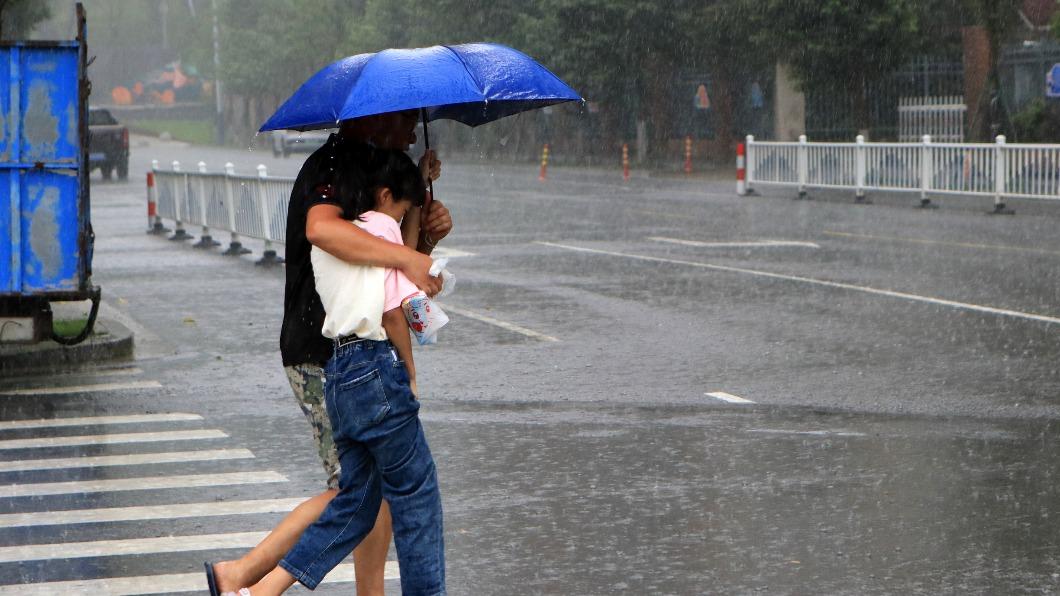 浙江台州居民在暴雨中行走。(圖/翻攝自《澎湃新聞》)