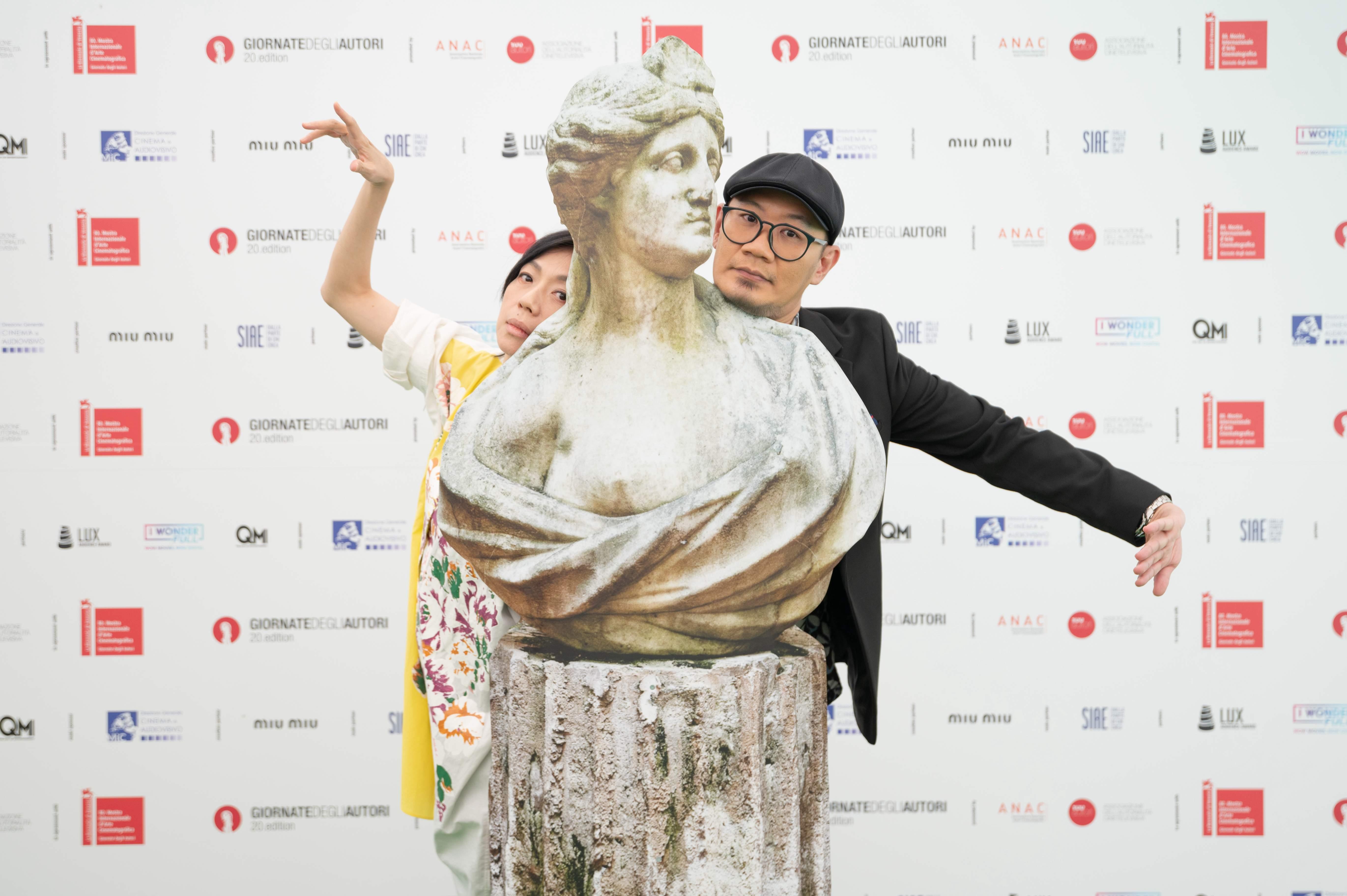 《五月雪》導演張吉安(右)、演員萬芳在威尼斯影展世界首映,在第二十屆威尼斯日主視覺雕像前合影。(圖/Giulia Barini、Giornate Degli Autori提供)
