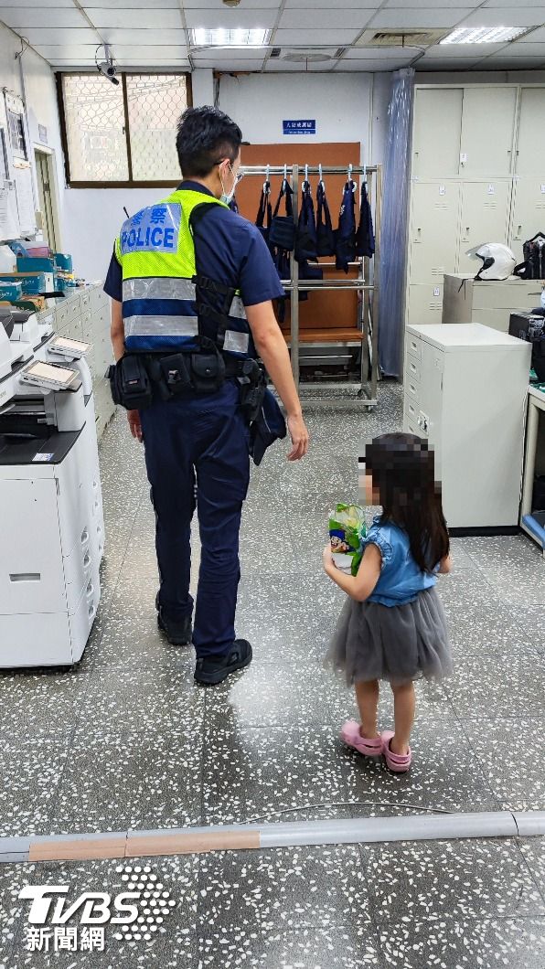 小女孩隨著員警回到派出所,手上還緊緊抱著零食。(圖/土城分局提供)