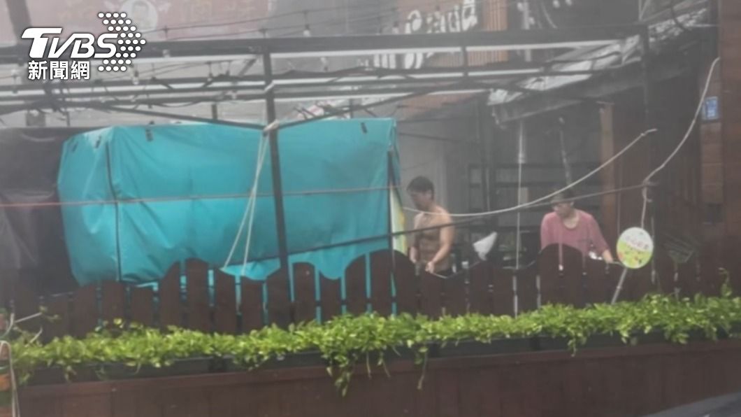 民眾在狂風暴雨中綁穩攤位。(圖/李昱菫攝)