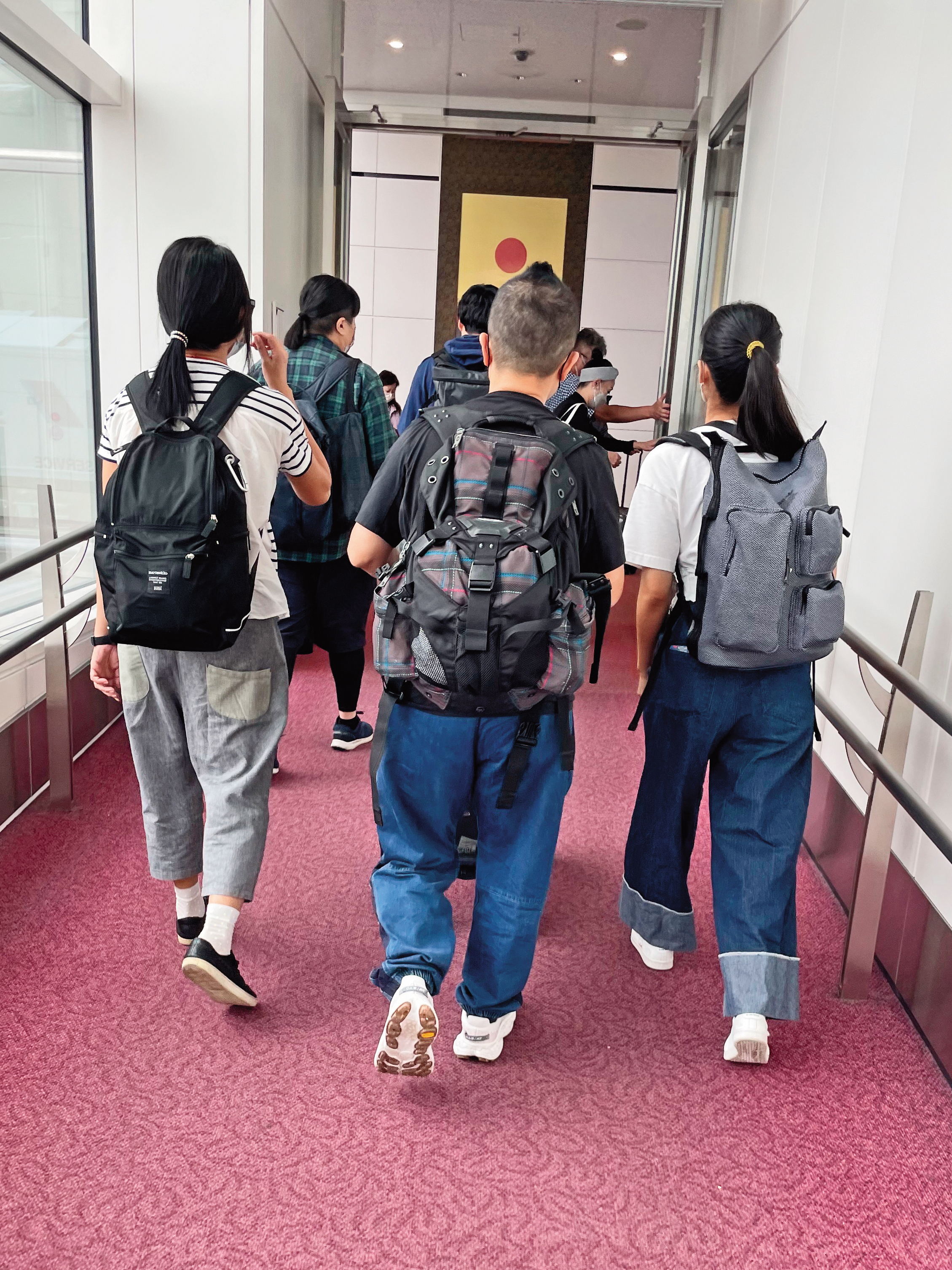九把刀帶著妻小前往東京,搭乘的航班抵達羽田機場,下機後一家人走在廊道上。(圖/讀者提供)