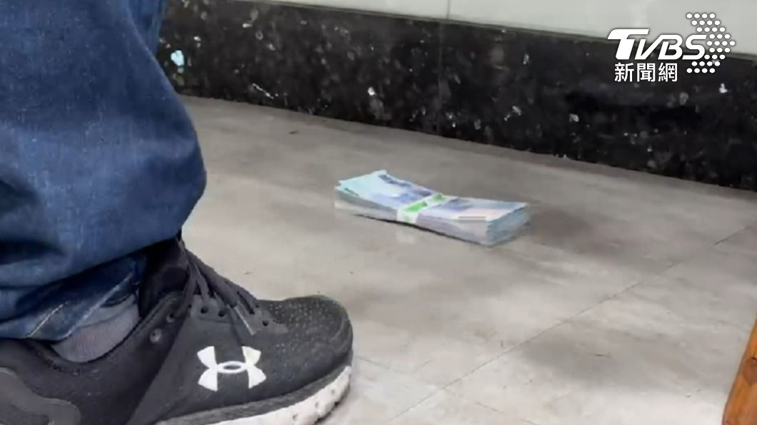 郵局行員點鈔時,誤將一疊掉在地上的10萬元現鈔踢進桌子底下。(圖/TVBS)
