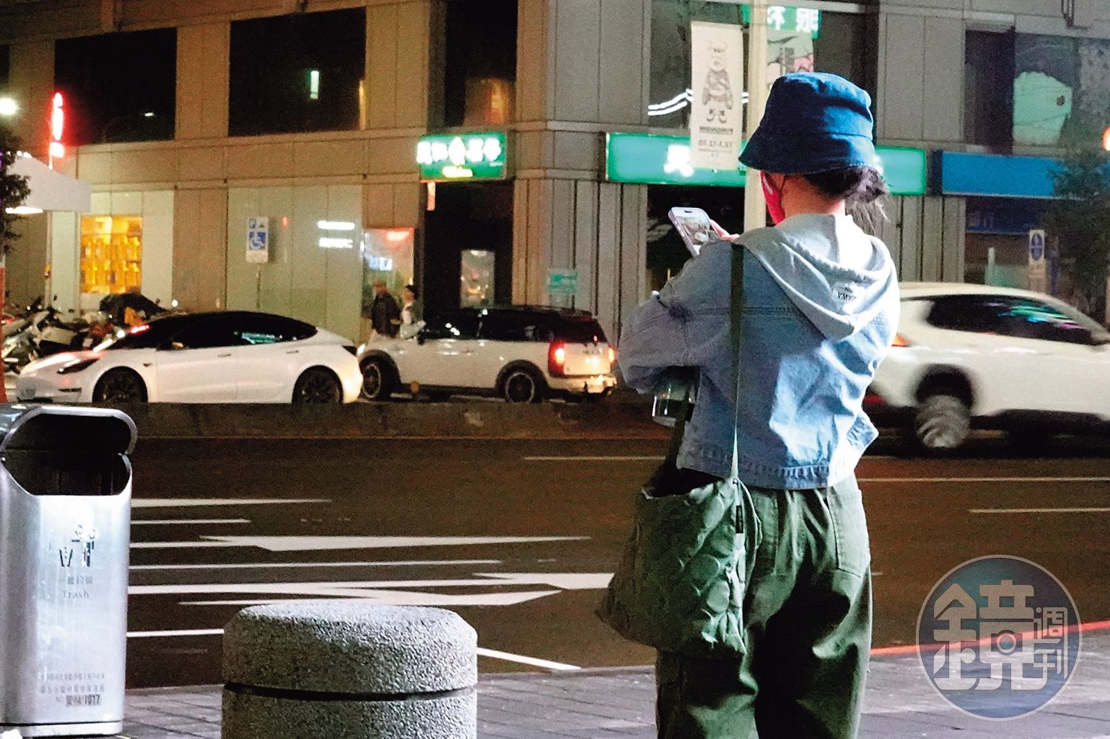 21:40 許藍方在公車站牌滑手機,滑著滑著動身前往買肉乾。(圖/鏡週刊)