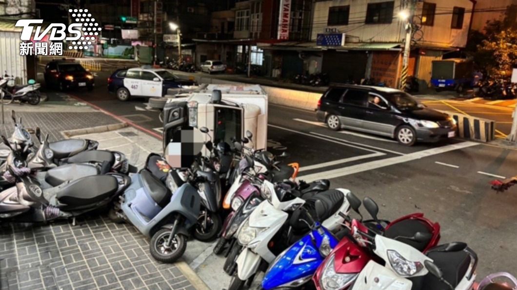 小貨車側翻後撞進停車格,13輛機車被波及。(圖/TVBS)