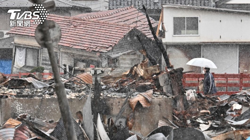 石川縣地震重災區輪島市,日本民眾撐傘避雪走過倒塌的房屋。(圖/達志影像美聯社)