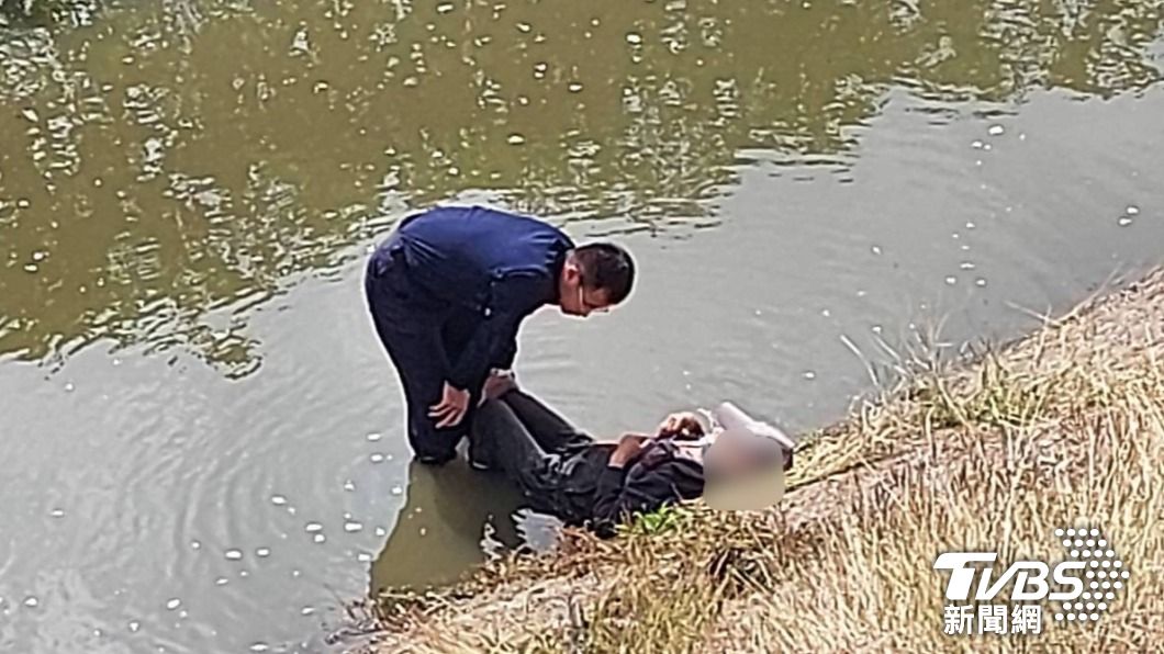 員警等待消防抵達期間,涉水將顏翁互助,避免其滑入水中。(圖/TVBS)