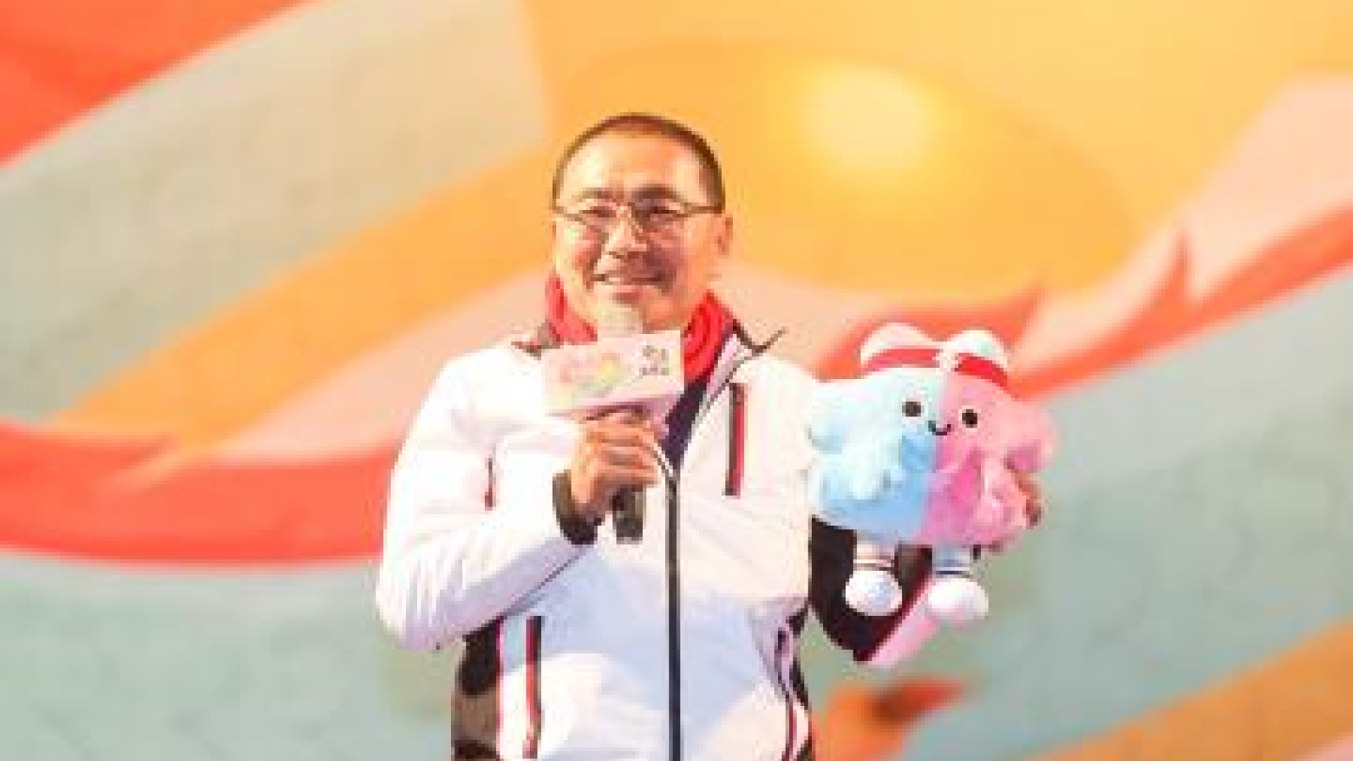 新北市侯友宜市長抱著可愛地世壯運吉祥物,介紹吉祥物外型如同個「北」字,配色藍色象徵冷靜勇敢、粉紅色則有熱情活力的意味。