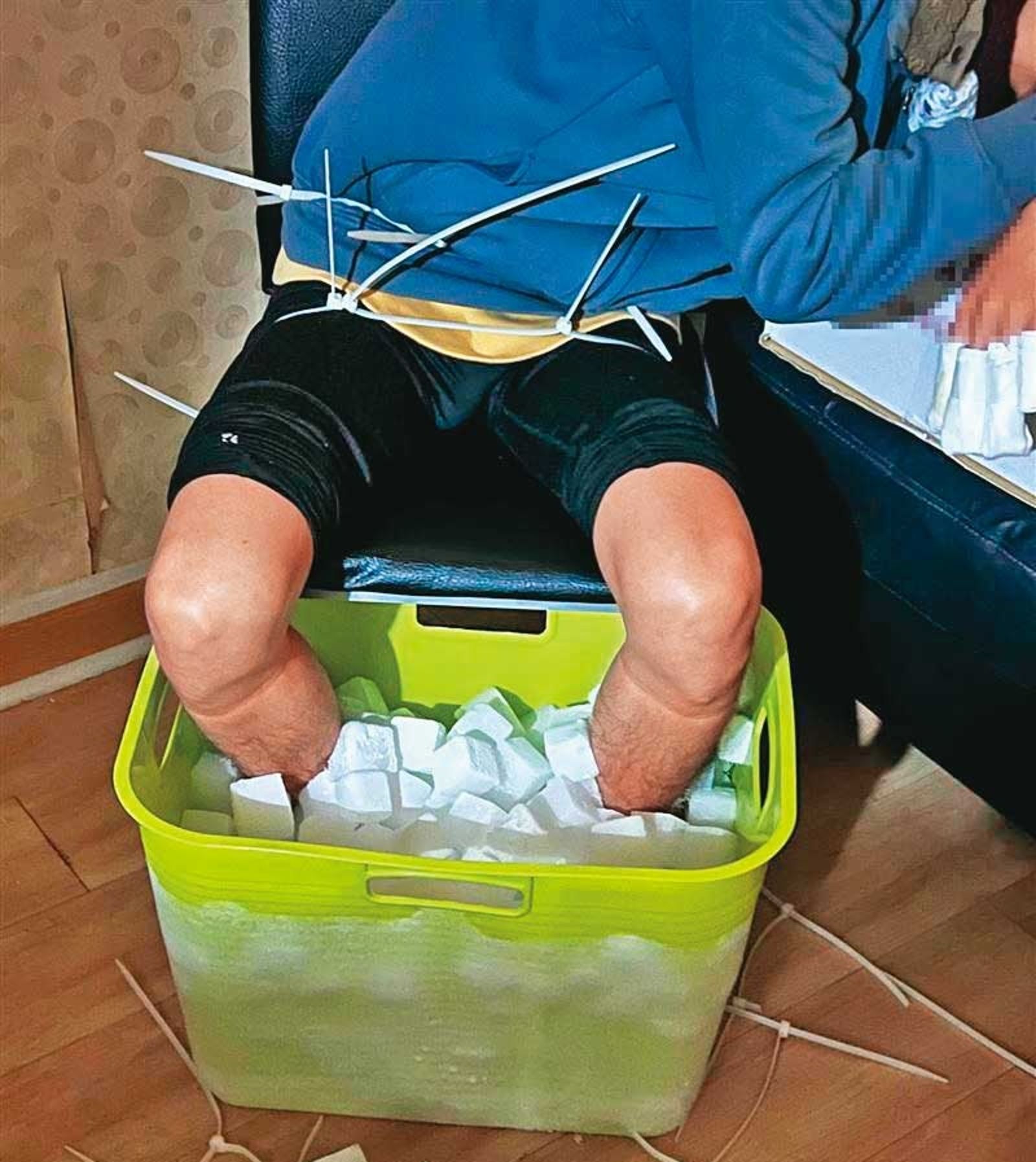 張男的大腿及腰部被束帶固定住,避免他因受不了寒冷把腳從乾冰桶中抬起。(圖/翻攝畫面)