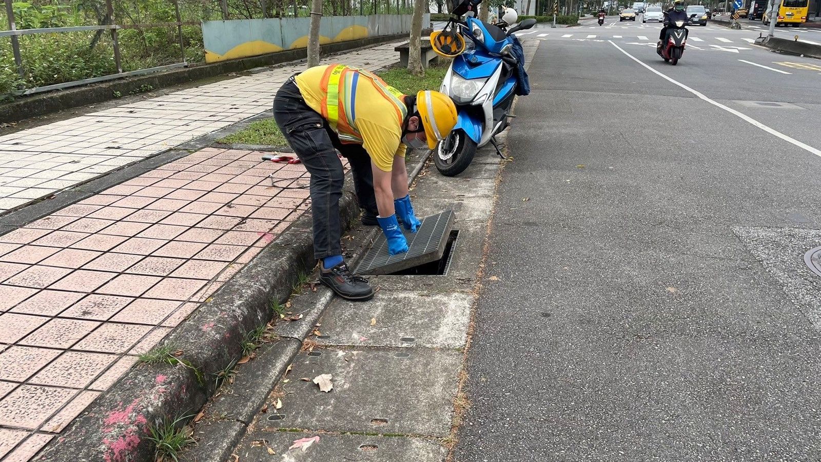 清潔隊員戴上橡膠手套，打開水溝井蓋尋找民眾掉落的失物。（圖／北市環保局提供）
