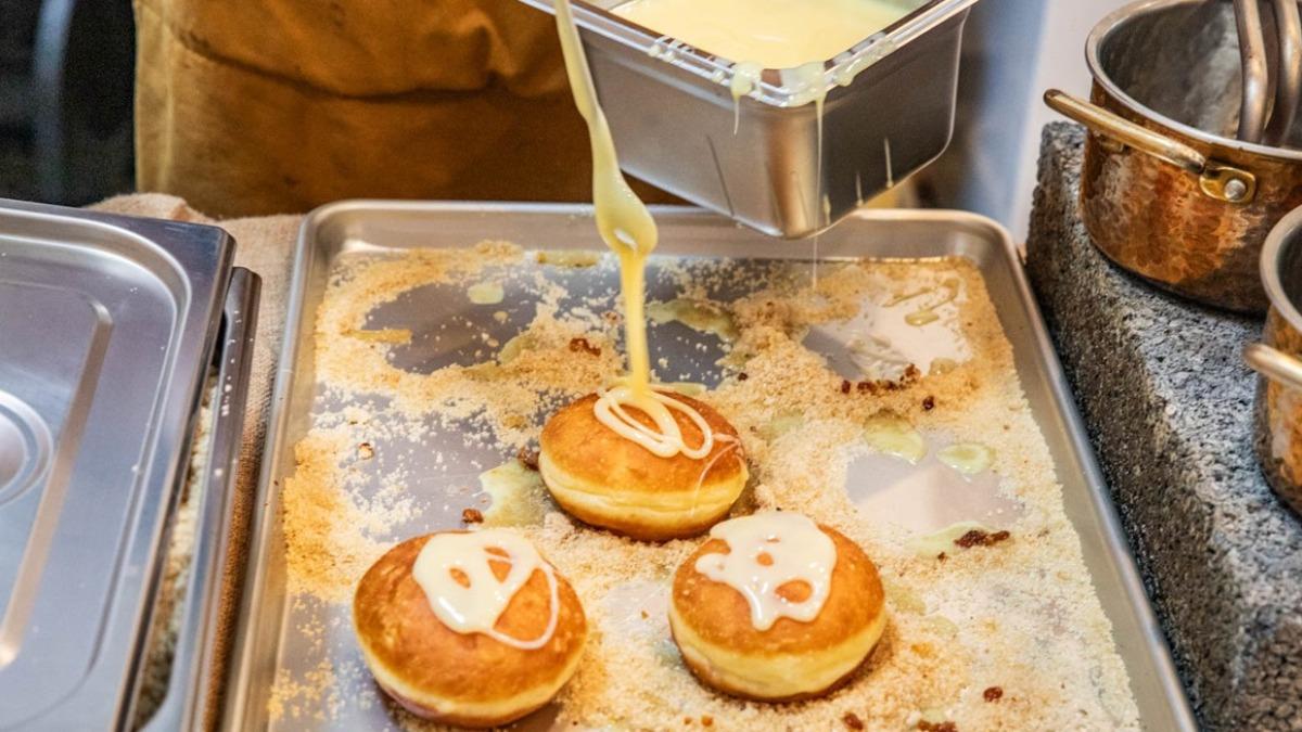製作過程會先將煉乳淋在甜甜圈上。(圖/大手牽小手。玩樂趣提供)