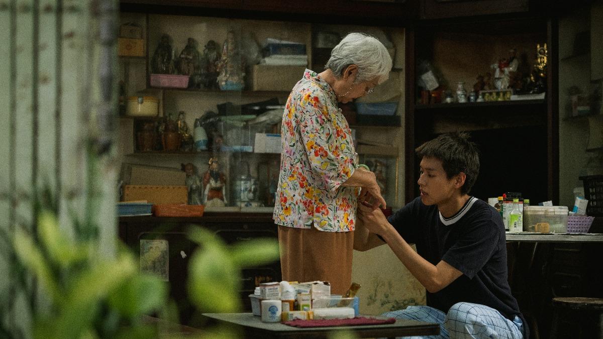 金孫幫阿嬤扣衣服,照顧的無微不至。(圖/CATCHPLAY提供)