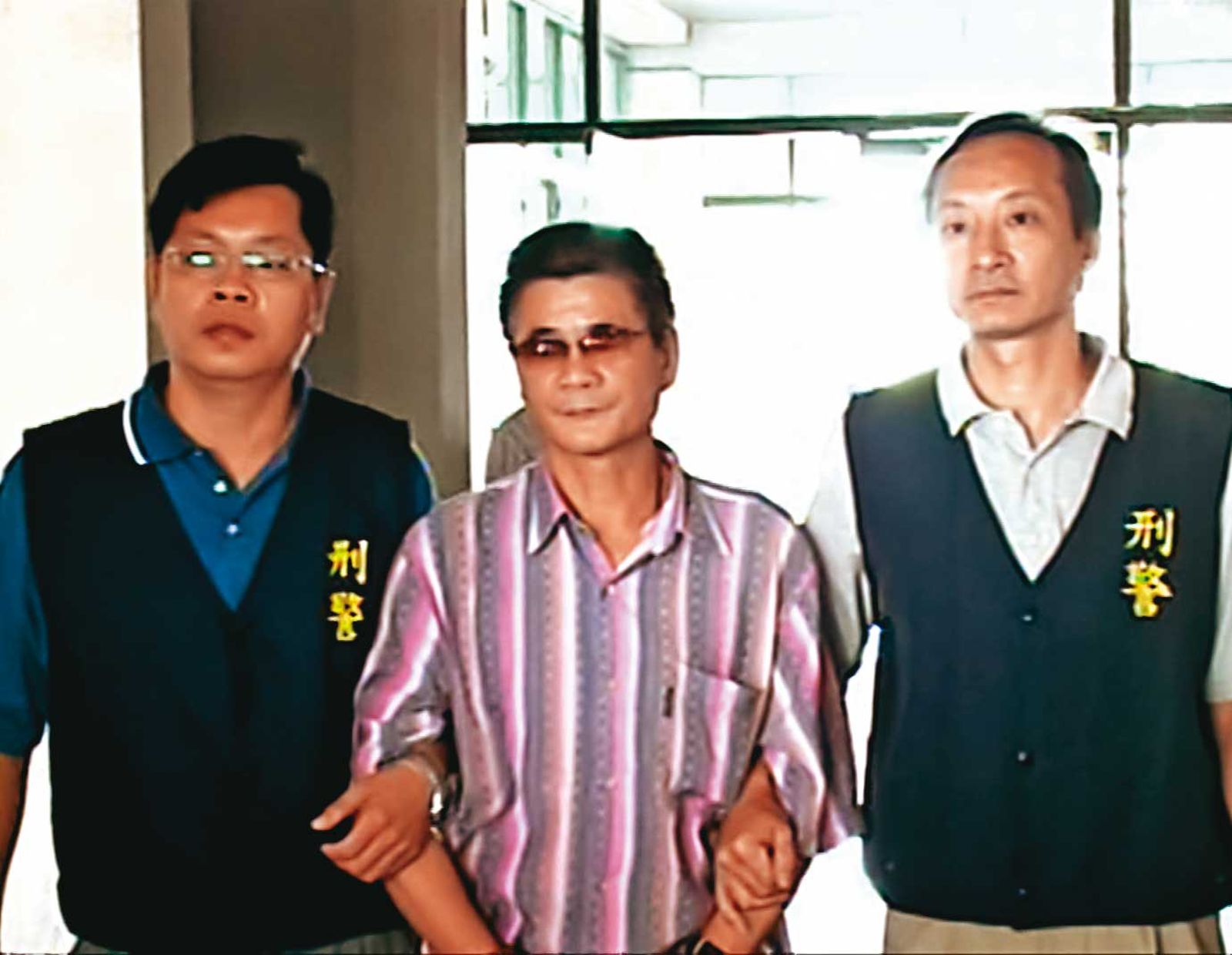 王信福(中)潛逃中國多年,因想返台治療眼疾,遭警方逮捕。(圖/東森新聞提供)