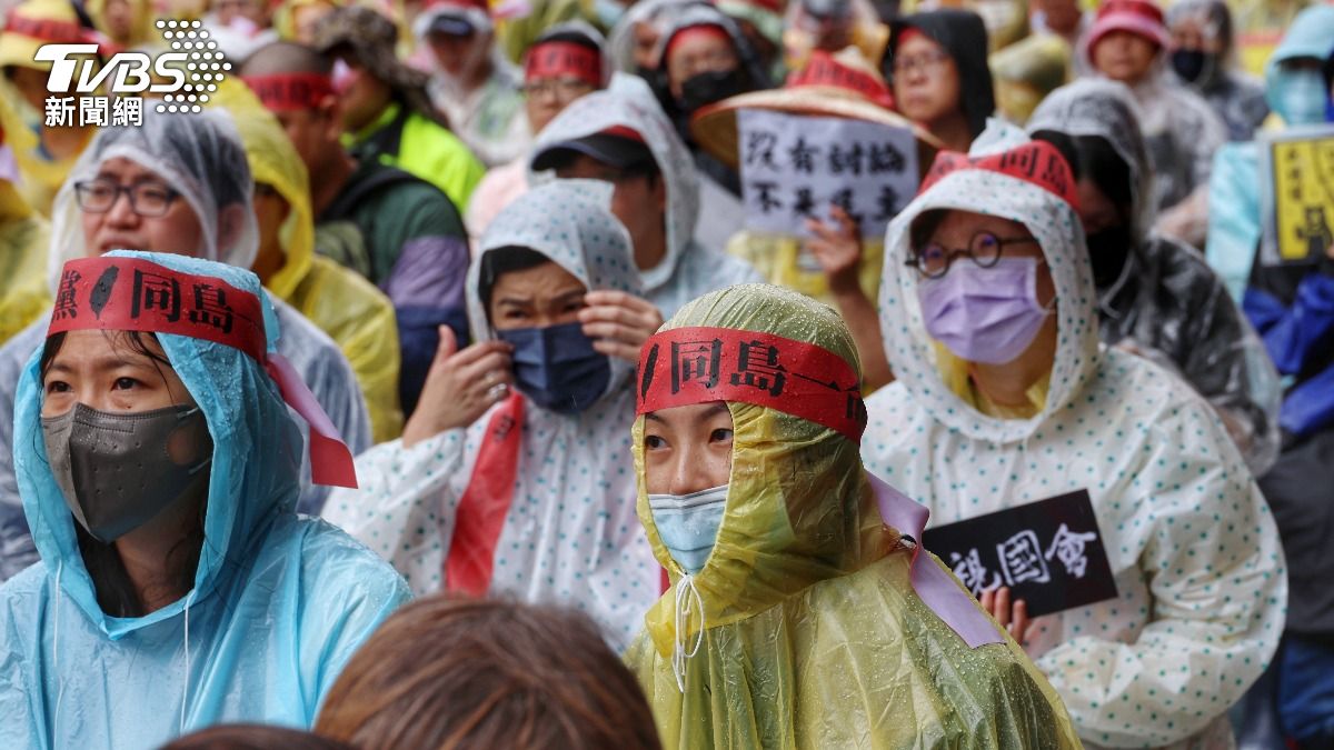 抗議民眾穿上雨衣,不畏風雨持續在場外關注。(圖/葉志明攝)