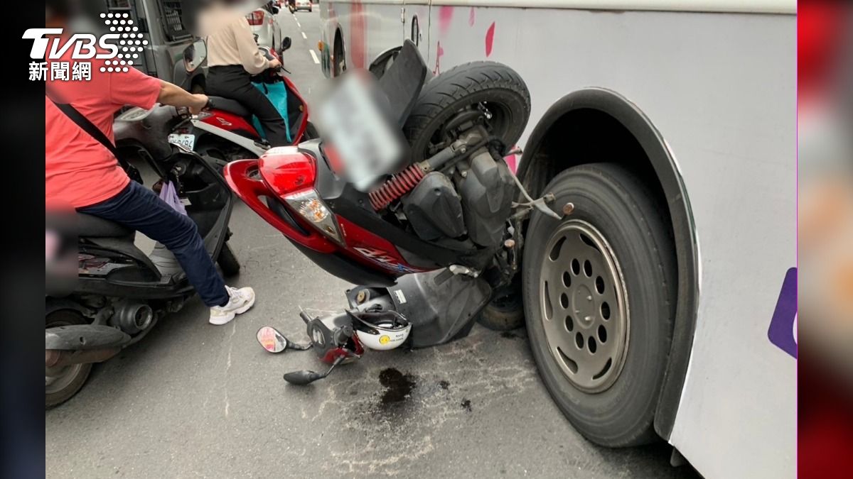 機車呈現「倒立」的狀態卡在公車底下,引起路人側目。(圖/TVBS)