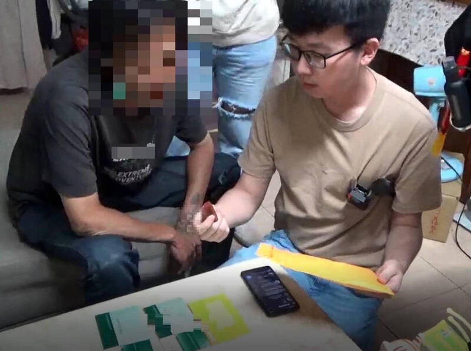 草屯警分局員警逮住謝男，在他面前將存摺和印章取出清點。（圖／翻攝自畫面）