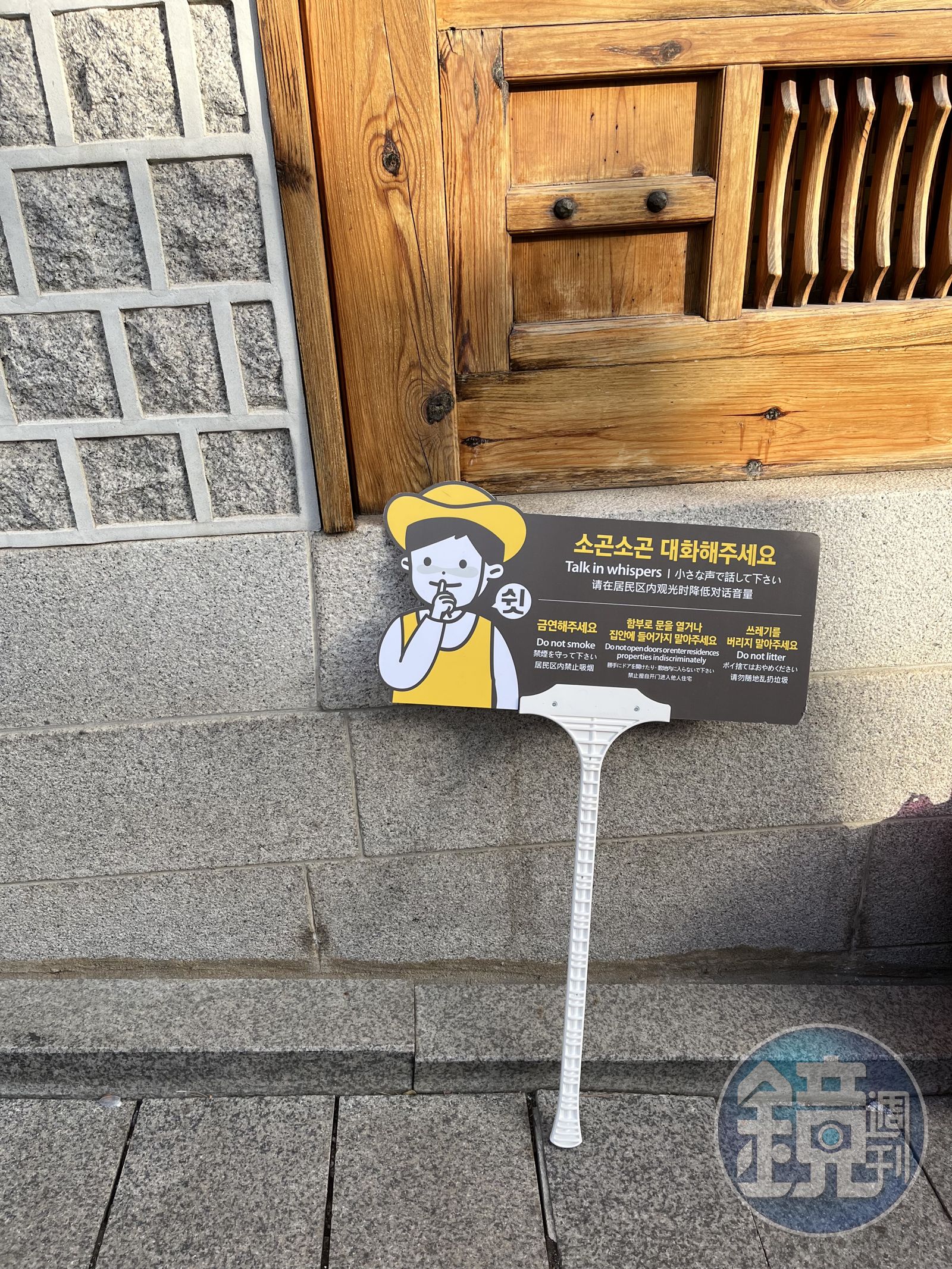 北村韓屋村因為遊客眾多,就有工作人員舉牌提醒控制音量,避免影響居民。(圖/鏡週刊)