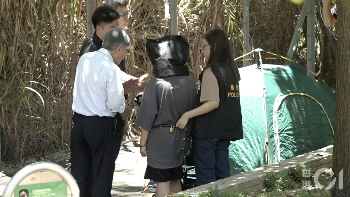 女嫌犯頭蓋黑布被鐵鍊拴住，帶到現場模擬犯案過程。（圖／香港01）
