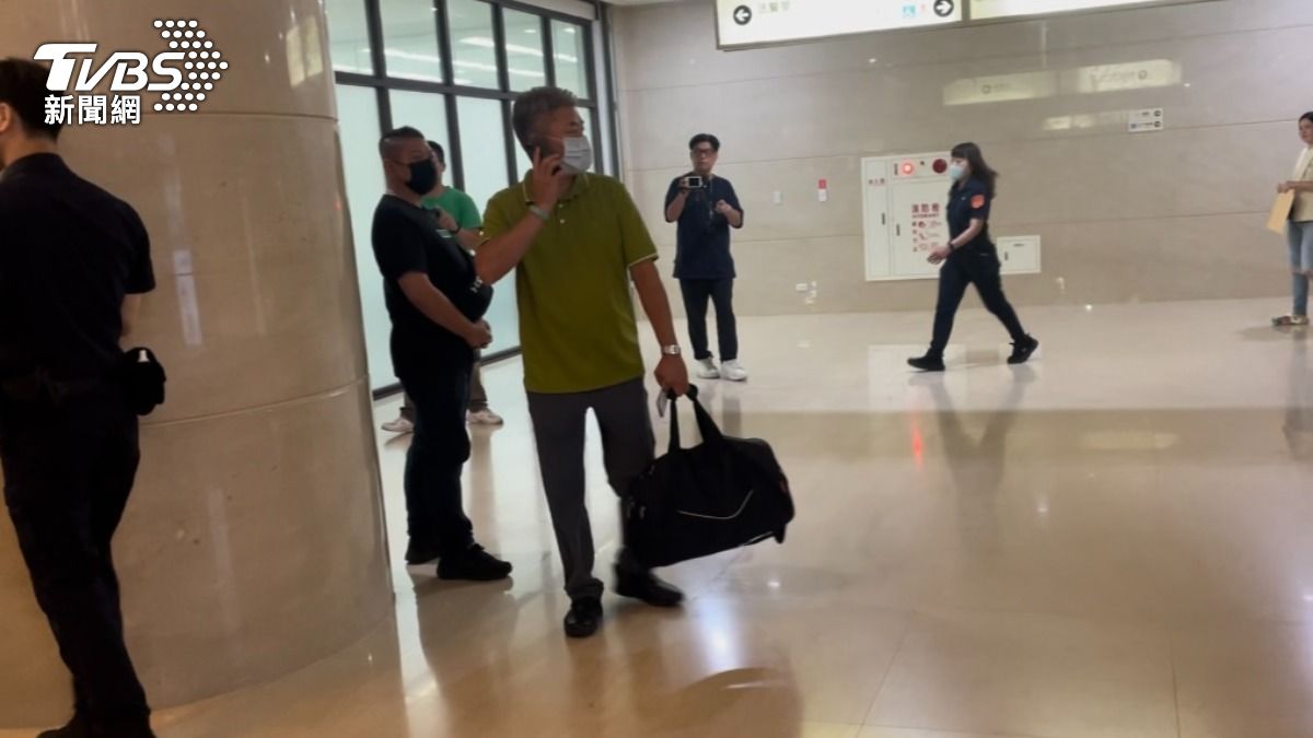 綠衣男提著黑色行李袋,裝著千元現鈔來到法院。(圖/潘千詩攝)