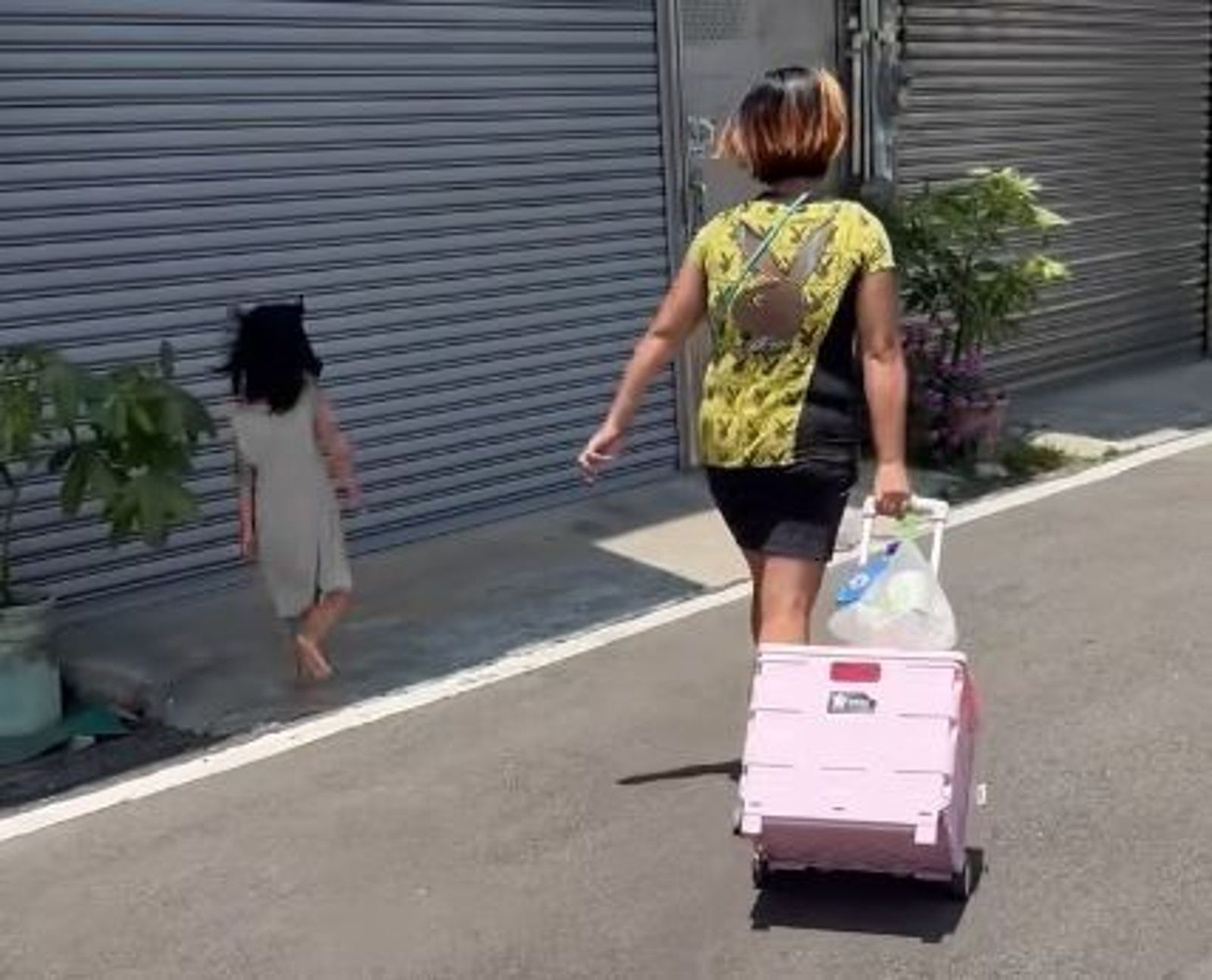 小孩子受不了疼痛,試圖躲到陰影處,卻被媽媽一把拉回太陽底下繼續踩在滾燙的柏油路上走。(圖/翻攝自臉書社團「新竹大小事」)