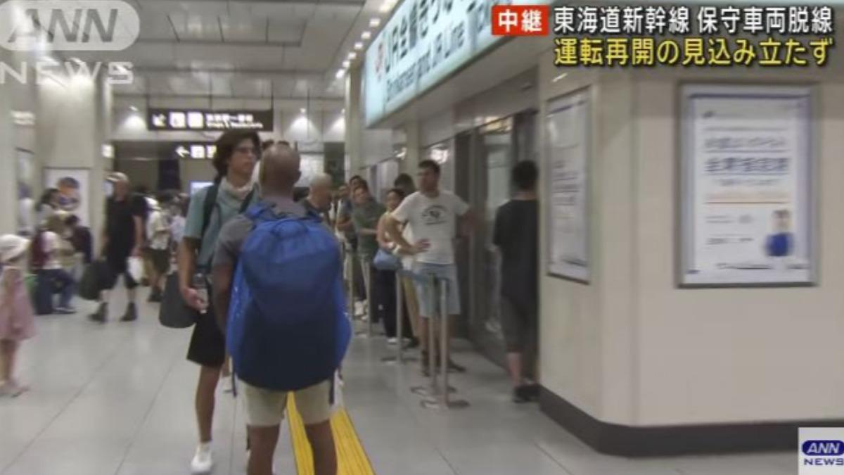 東海道及山陽新幹線驗票口前豎立了暫停行駛的告示牌，許多人在站內駐足查看最新情況，以及向車站工作人員詢問最新復駛資訊。（圖／擷取自ANN NEWS）