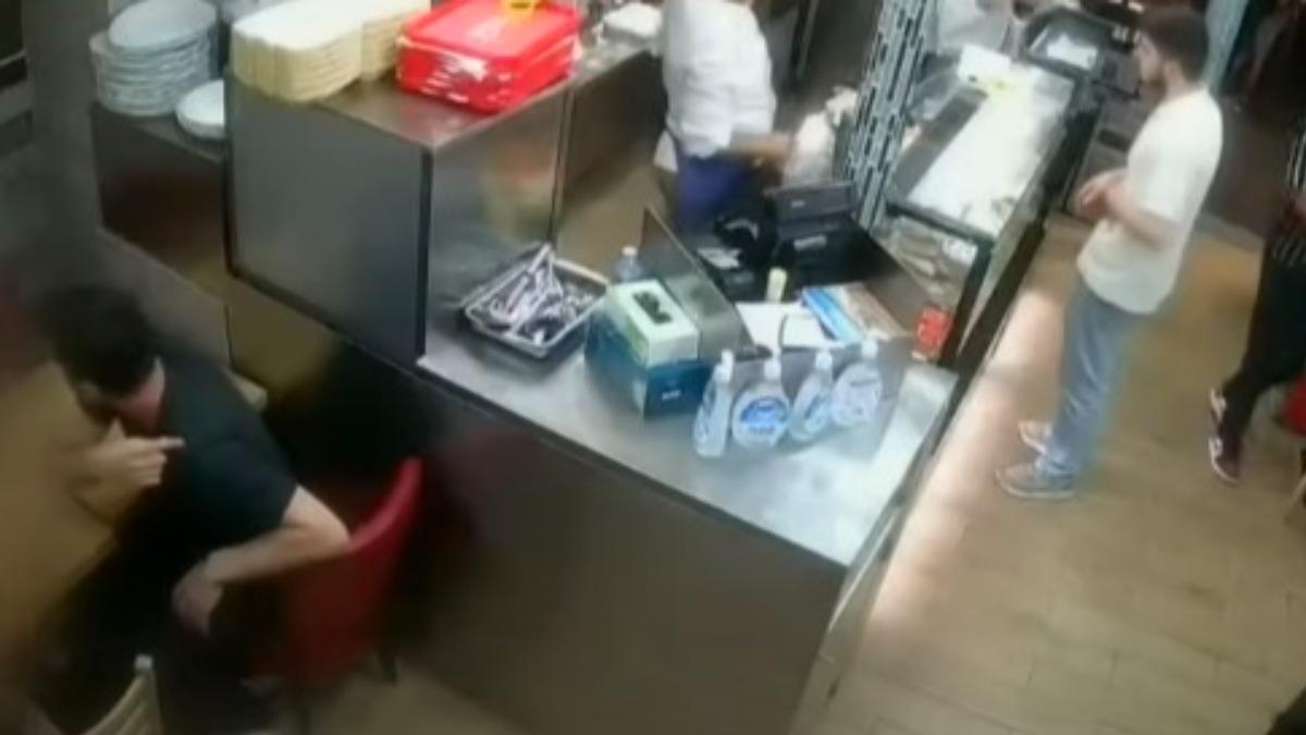 受害女子蜷縮在烤肉店角落的座位(畫面左側外),隨後有民眾(畫面左側黑衣男子)上前關心。(圖/翻攝自YouTube@7NEWS)