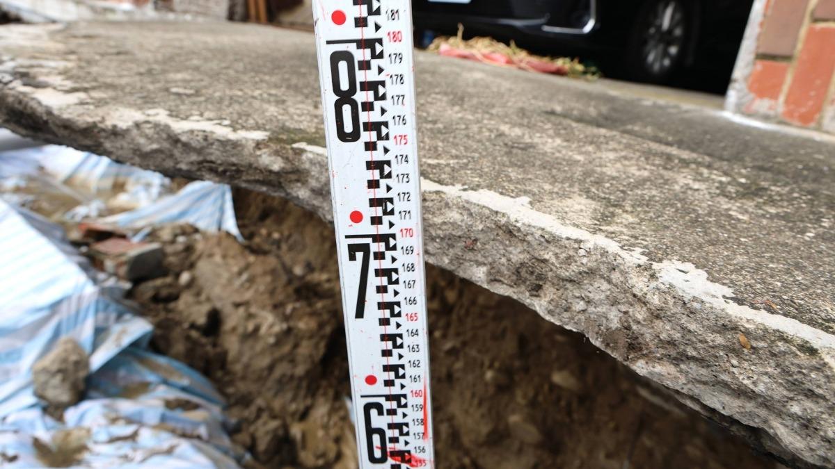 許淑華昨日前往會勘,測量社區道路下陷與臨路民宅的高差,最深已達180公分。(圖/南投縣政府提供)