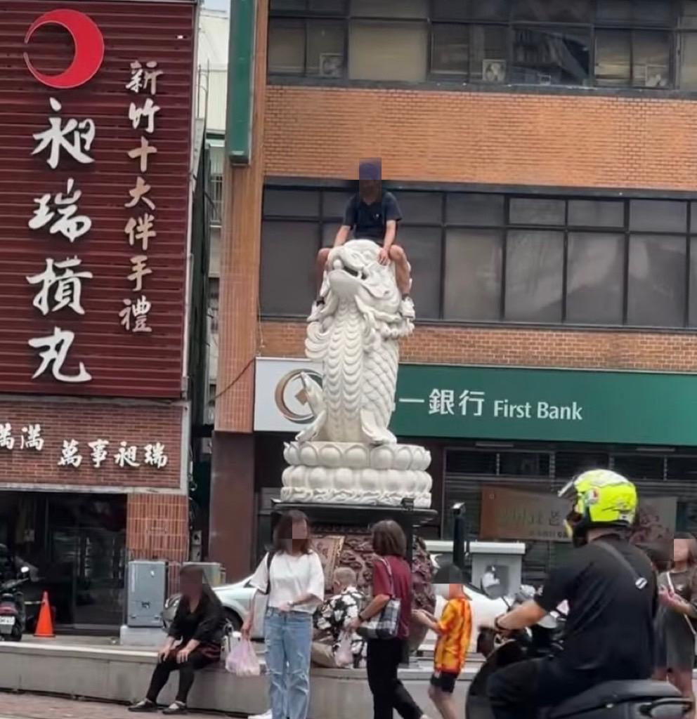 一名男子疑似攀爬到龍鯉石雕的頂端。(圖/翻攝自臉書)