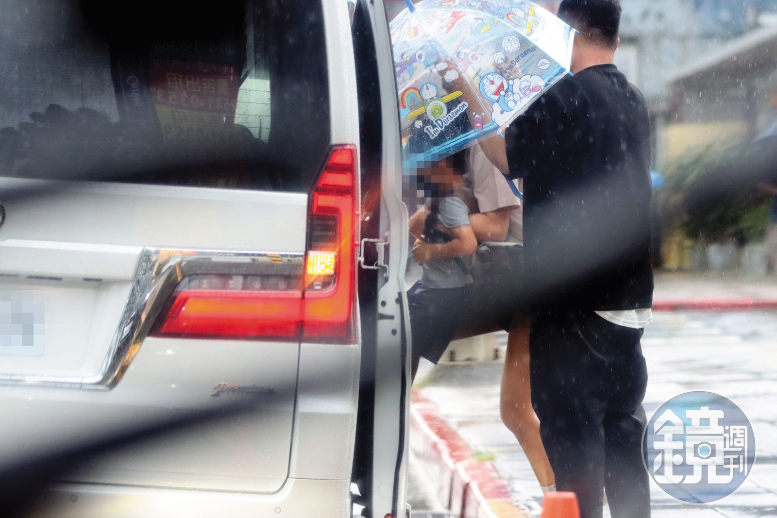 8/15 16:22 安以軒(中)必須手與膝蓋並用,才能把五歲兒子弄上車,此時還下著大雨,感覺更狼狽。(圖/鏡週刊)