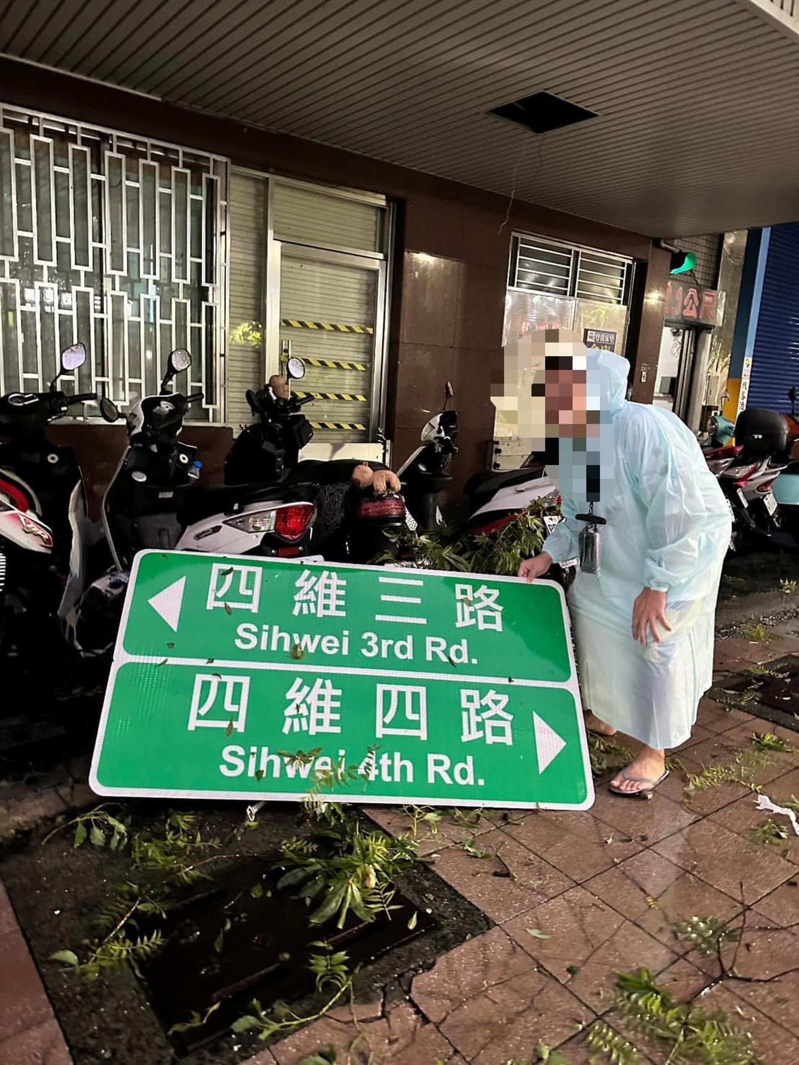 高雄人收拾家園之餘,與掉落的路牌合影。(圖/翻攝自高雄點臉書)